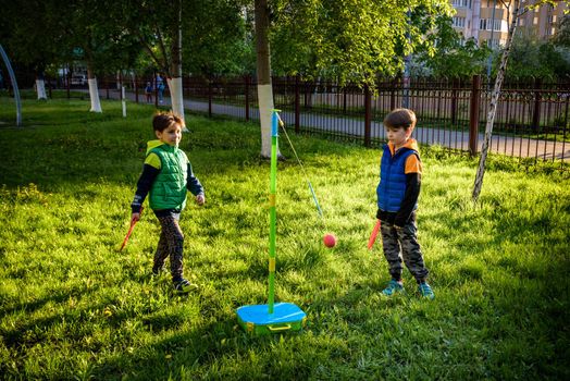 Two friends are playing tetherball swing ball game in summer camping. Two boy brother happy leisure healthy active time outdoors concept.