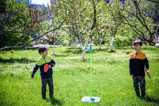 Two friends are playing tetherball swing ball game in summer camping. Two boy brother happy leisure healthy active time outdoors concept.