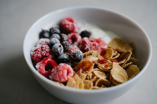 Healthy breakfast with berries, cereals and natural yogurt. Multi-lacquered cereals for breakfast. Berries in ice. Frozen raspberries and black currants. Delicious and healthy breakfast.