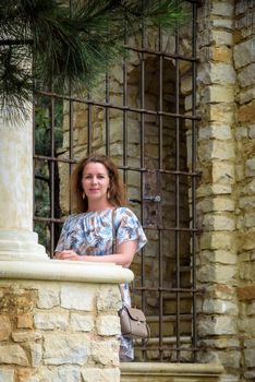 Portrait of young pretty woman on stairs near ancient historical building from stone and seashells.