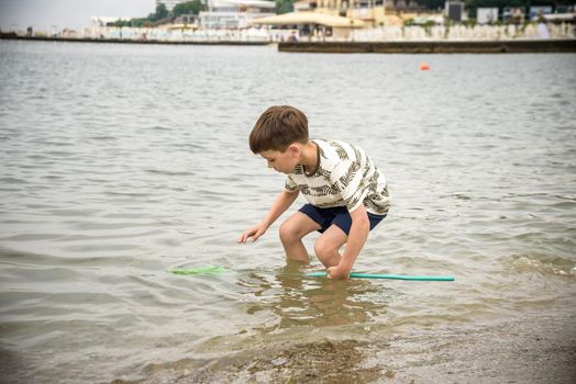 One little boy alone exploring the beach at low tide walking towards the sea coast. happy childhood concept.