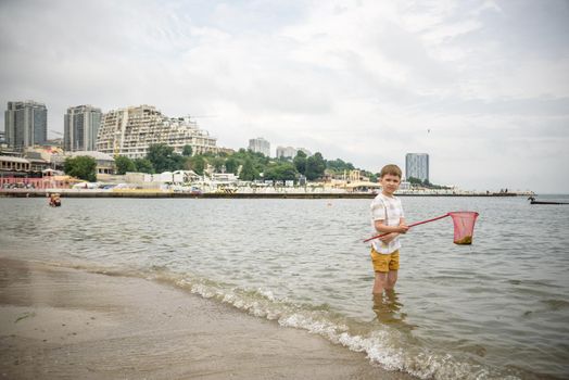 One little boy alone exploring the beach at low tide walking towards the sea coast. happy childhood concept.