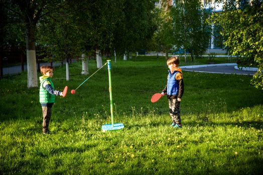 Two friends are playing tetherball swing ball game in summer camping. Two boy brother happy leisure healthy active time outdoors concept.