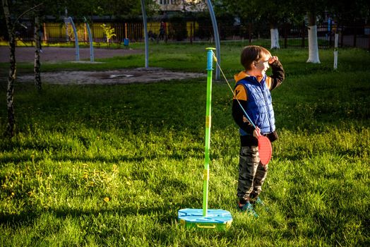 Happy boy is playing tetherball swing ball game in summer camping. Happy leisure healthy active time outdoors concept.