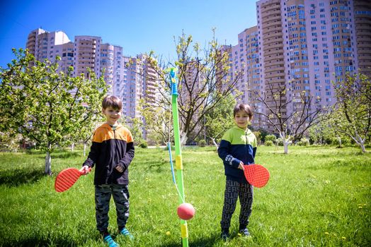 Two friends are playing tetherball swing ball game in summer camping. Two boy brother happy leisure healthy active time outdoors concept.