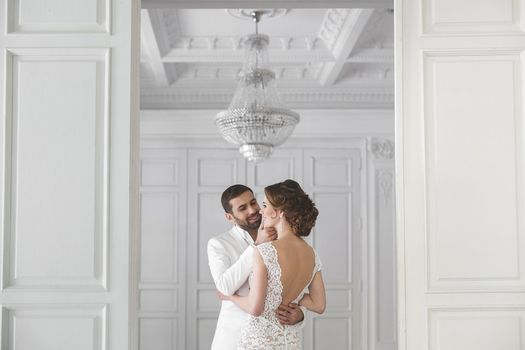 Chic wedding couple groom and bride posing in a white Studio.