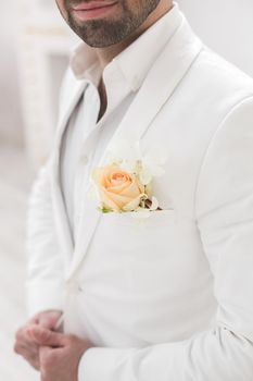 Elegant young handsome man with a beard in a white classic suit.