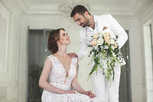 Chic wedding couple groom and bride posing in a white Studio.