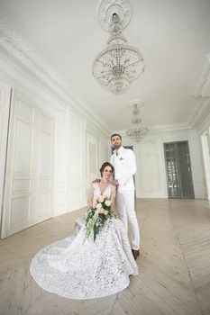 Chic wedding couple groom and bride posing in a white Studio.