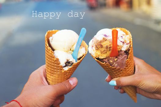 Beautiful bright ice cream with different flavors in the hands of a couple.