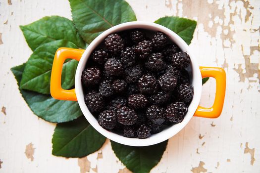 A full blackberry plate is on an old wooden background.