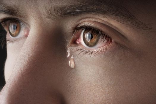 Closeup of young crying man eyes with a tears. High quality photo