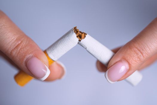 Closeup woman hands with broken cigarette. Stop smoking, quit smoking or no smoking concept. High quality photo