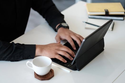 Close up hand of businessman using laptop computer keyboard at the office.