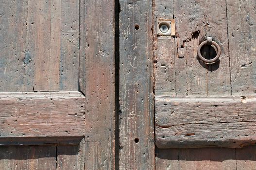 fragment  of ancient weathered wooden door with rusty ring handle
