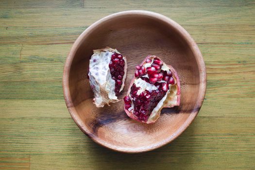 broken red juicy pomegranate in wooden bowl