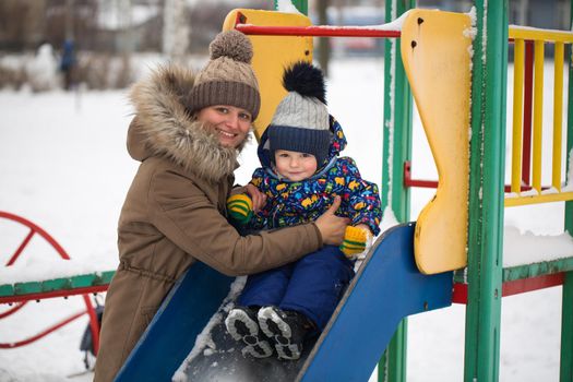 happy mother and baby in winter park. family outdoors. cheerful mommy with her child