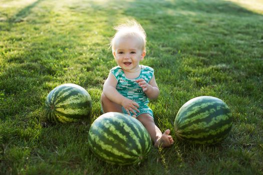 Little boy with a watermelon sitting on the grass