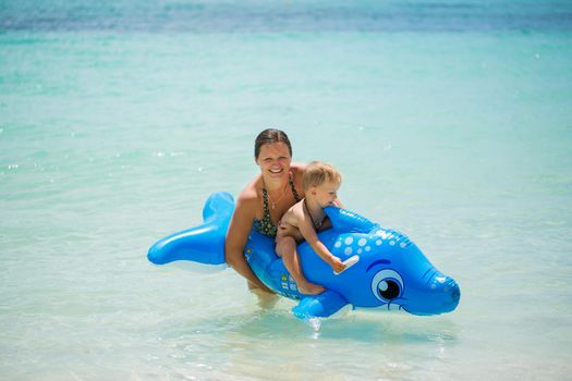 Mother and son swimming in the ocean on an inflatable Dolphin