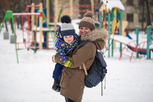 happy mother and baby in winter park. family outdoors. cheerful mommy with her child