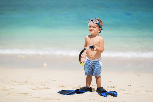 Little boy with diving mask and fins go swim at beach