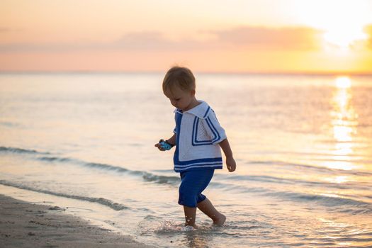 Boy on the beach. Wooden boat on the horizon.