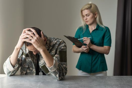 Female doctor and worried military officer discussing about problems he has during psychotherapy treatment