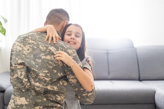 Little child is very happy her father came back from army. Little kid is hugging her father