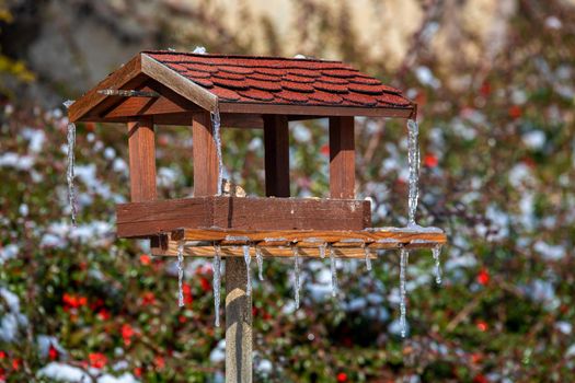 homemade wooden birdhouse, bird feeder installed on frozen snowy winter garden