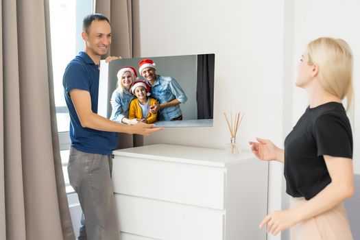 family holding photo canvas with christmas picture.