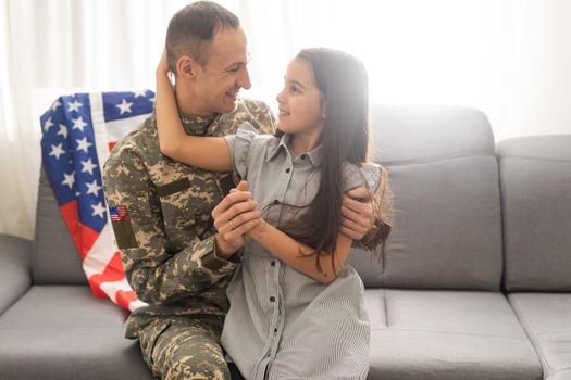 a child girl hugs a military father. dad in military uniform with his daughter. the veteran's return to the family.