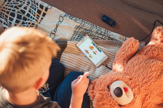 LOS ANGELES, CA, USA - OCTOBER 1, 2018: A phone with an educational game for a 5 year old child lies on the bed. A child plays on the phone, illustrative editorial