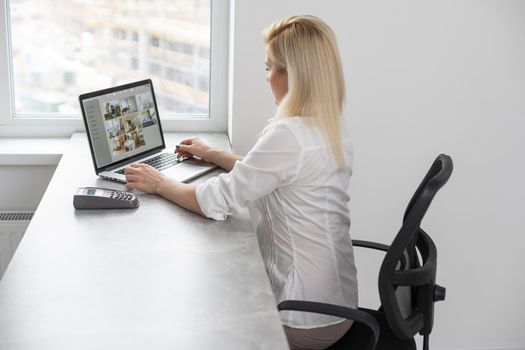 Back view of businesswoman speak using Webcam conference on laptop with diverse colleagues, female employee talk on video call with multiracial coworkers engaged in online briefing from home