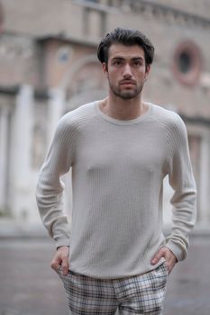 beautiful guy with white sweater in the center of reggio emilia. High quality photo
