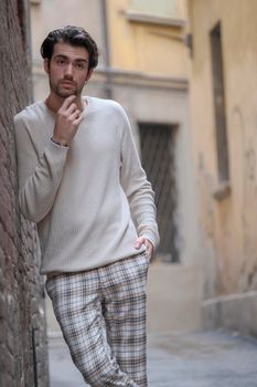 beautiful guy with white sweater in the center of reggio emilia. High quality photo