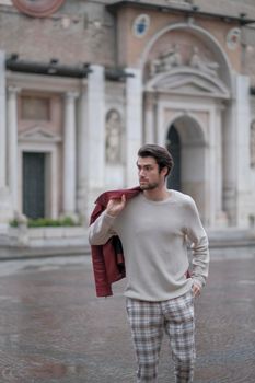 beautiful guy with red leather jacket and backpack in the center of reggio emilia. High quality photo