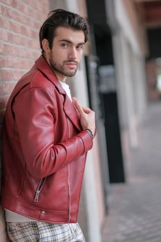 beautiful guy with red leather jacket and backpack in the center of reggio emilia. High quality photo