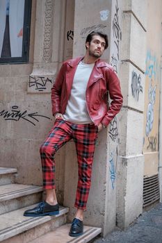 beautiful guy with red leather jacket and backpack in the center of reggio emilia. High quality photo