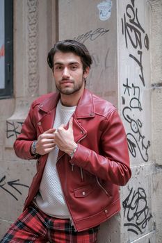 beautiful guy with red leather jacket and backpack in the center of reggio emilia. High quality photo