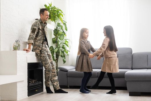 Happy veteran soldier comes back from the military and reunites with family. two children missed, home background.