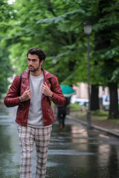 beautiful guy with red leather jacket and backpack in the center of reggio emilia. High quality photo