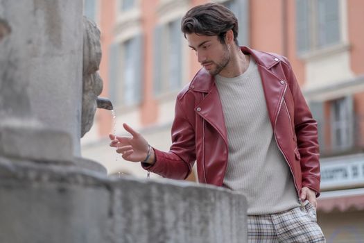 beautiful guy with red leather jacket and backpack in the center of reggio emilia. High quality photo