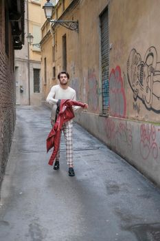 beautiful guy with red leather jacket and backpack in the center of reggio emilia. High quality photo