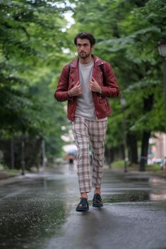 beautiful guy with red leather jacket and backpack in the center of reggio emilia. High quality photo