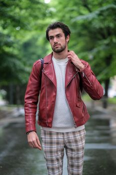 beautiful guy with red leather jacket and backpack in the center of reggio emilia. High quality photo