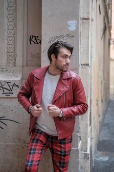 beautiful guy with red leather jacket and backpack in the center of reggio emilia. High quality photo