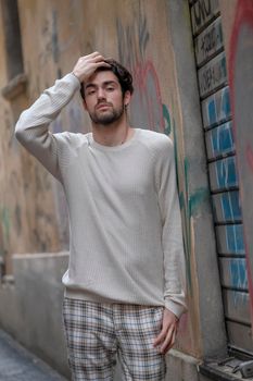 beautiful guy with white sweater in the center of reggio emilia. High quality photo