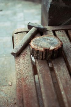 an old vintage hammer and a round bar of pine with sawdust on a bench. A wooden food stand for a master class. DIY concept.