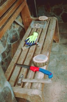 an old hammer, a hand saw, protective gloves and a round pine beam with sawdust on a bench. Wooden stand for food for the master class. DIY concept.