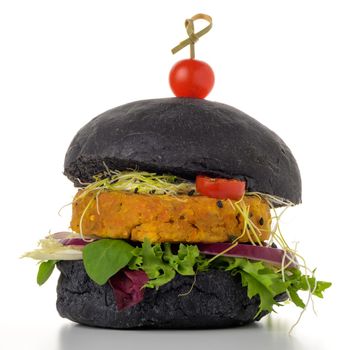 Tasty grilled veggie burger with chickpeas and vegetables on black bread on white background.